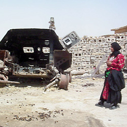 Frau im Irak vor einem Schrottpanzer